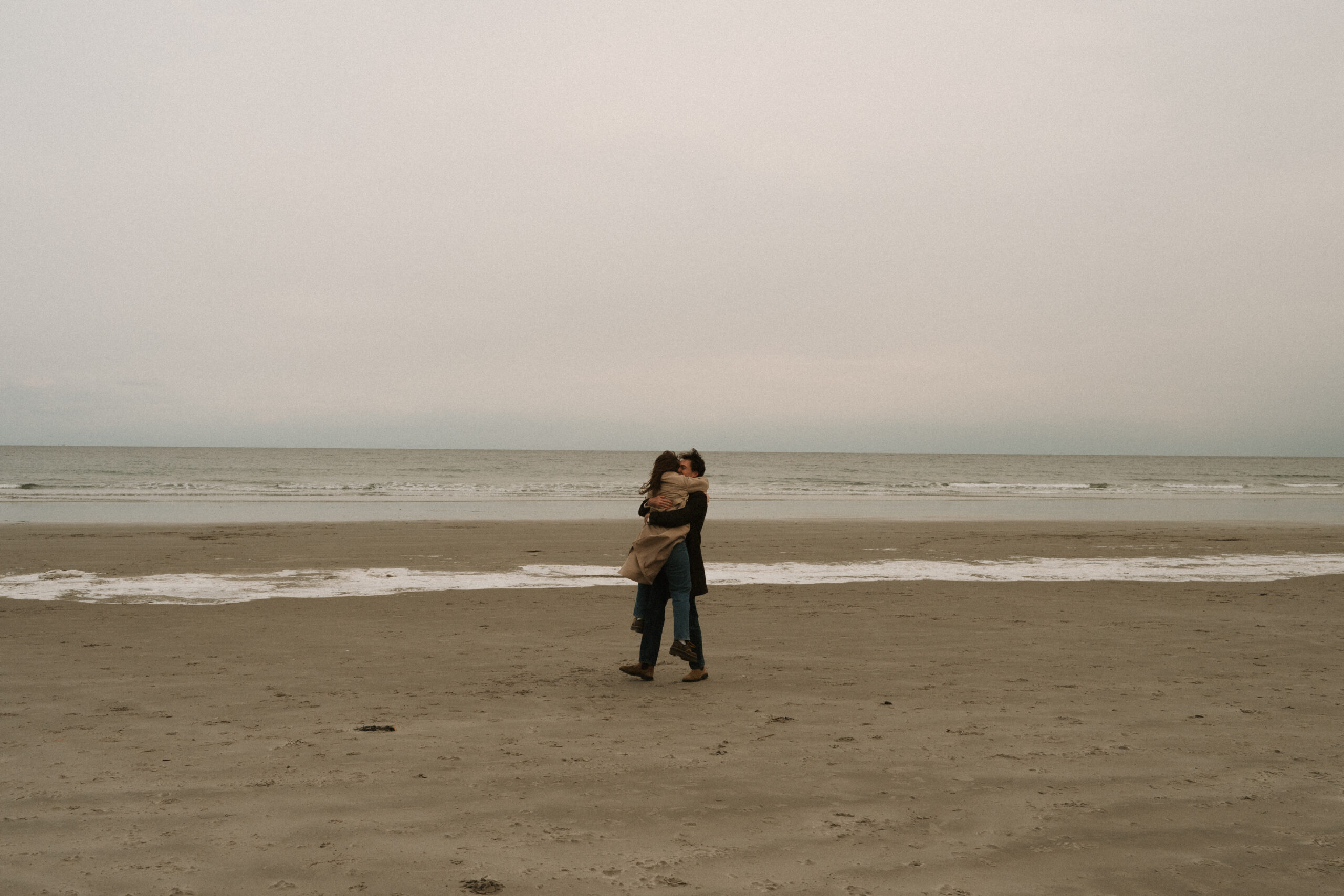 Moody coastal engagement session on the New Hampshire seacoast with overcast skies and ocean views