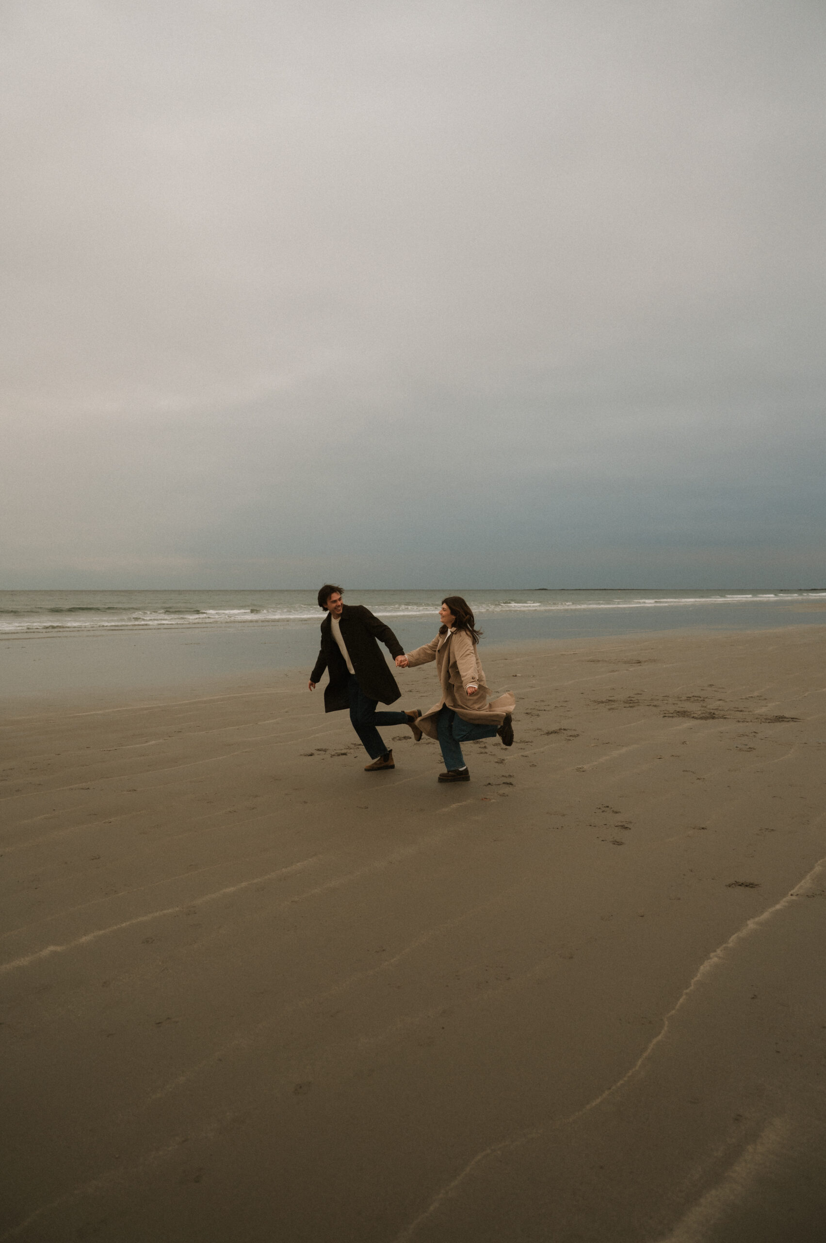 Romantic coastal New Hampshire engagement photography with dramatic clouds and shoreline