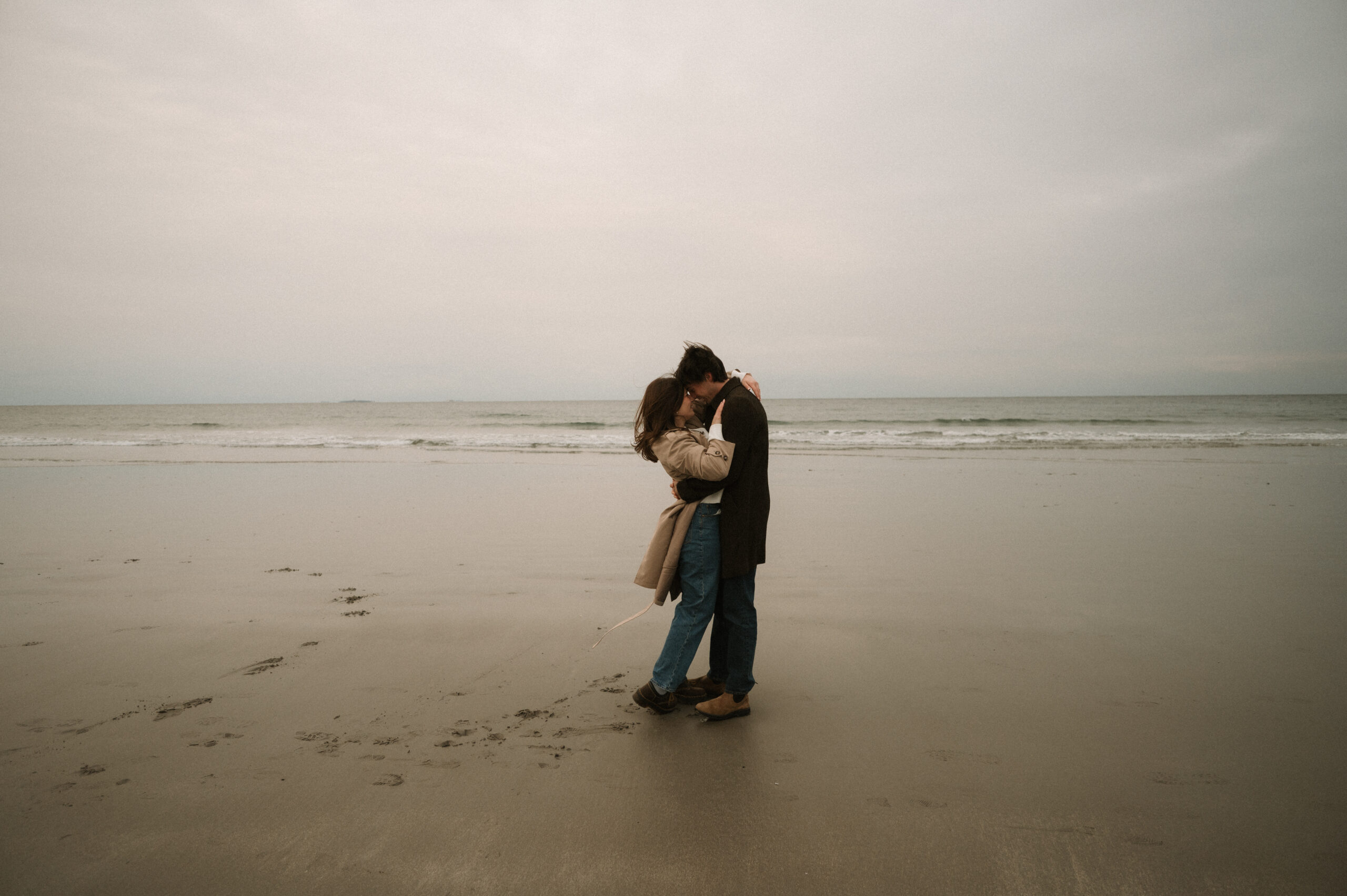 Cinematic New England engagement session with windswept ocean views and natural emotion