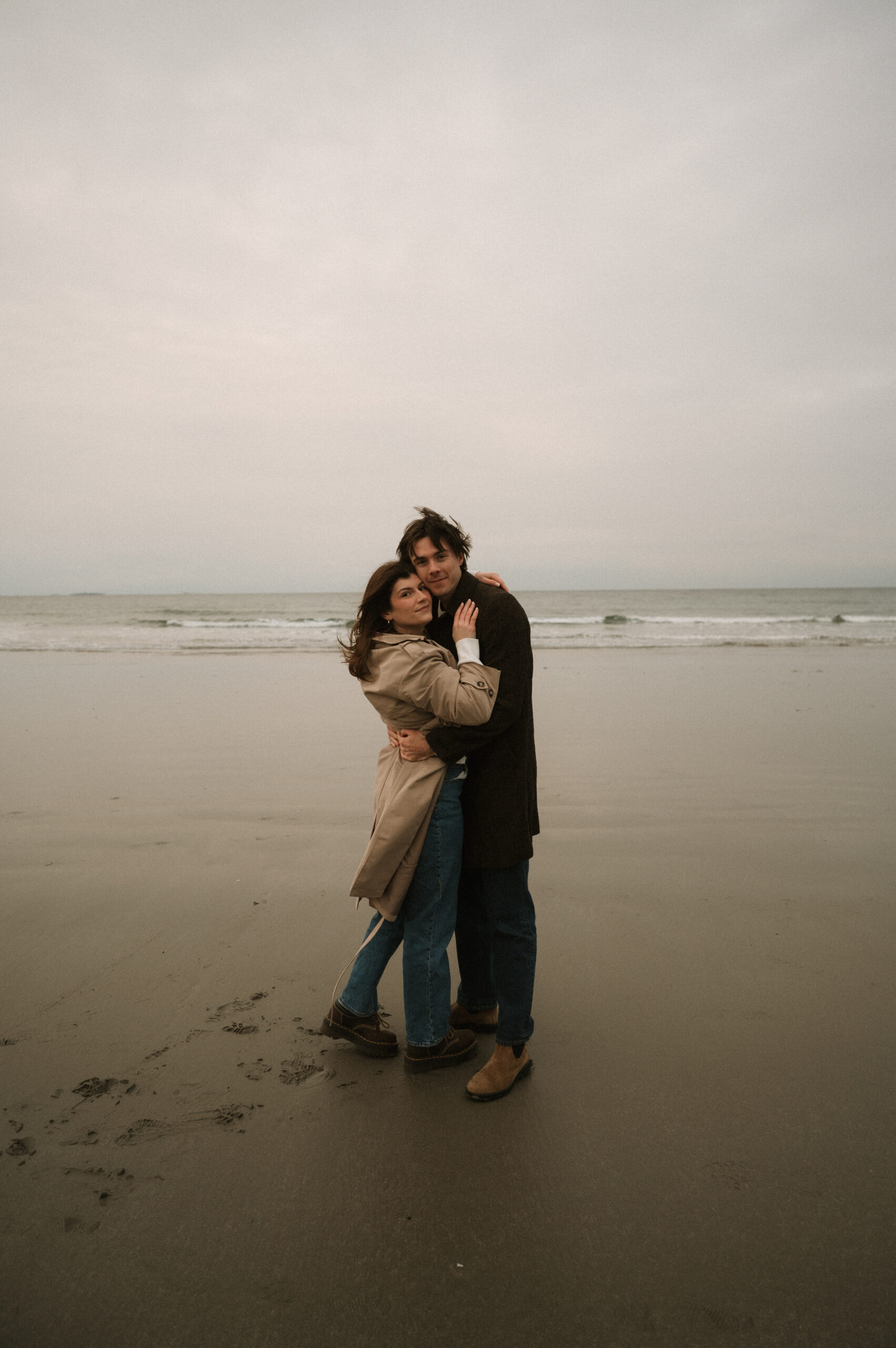 Cinematic New England engagement session with windswept ocean views and natural emotion