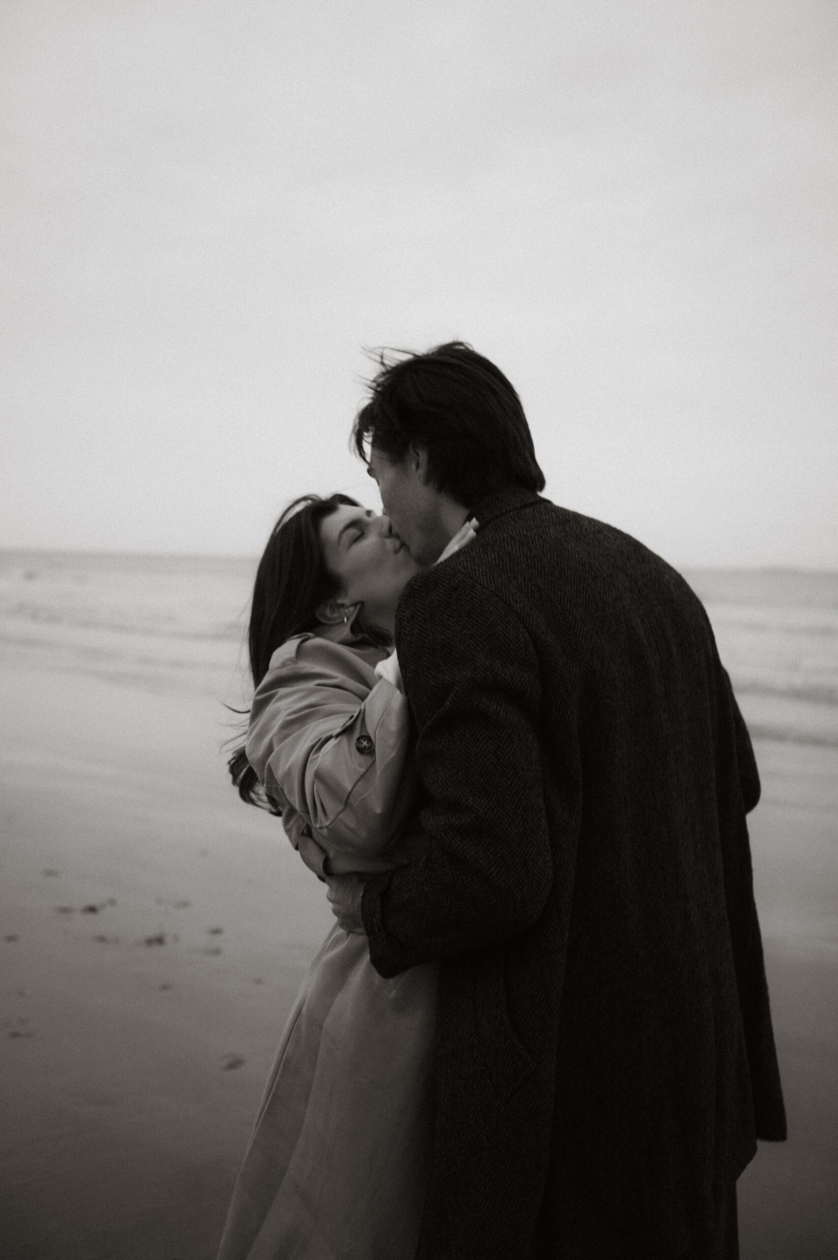 Cinematic New England coastal engagement session with dramatic skies and ocean horizons